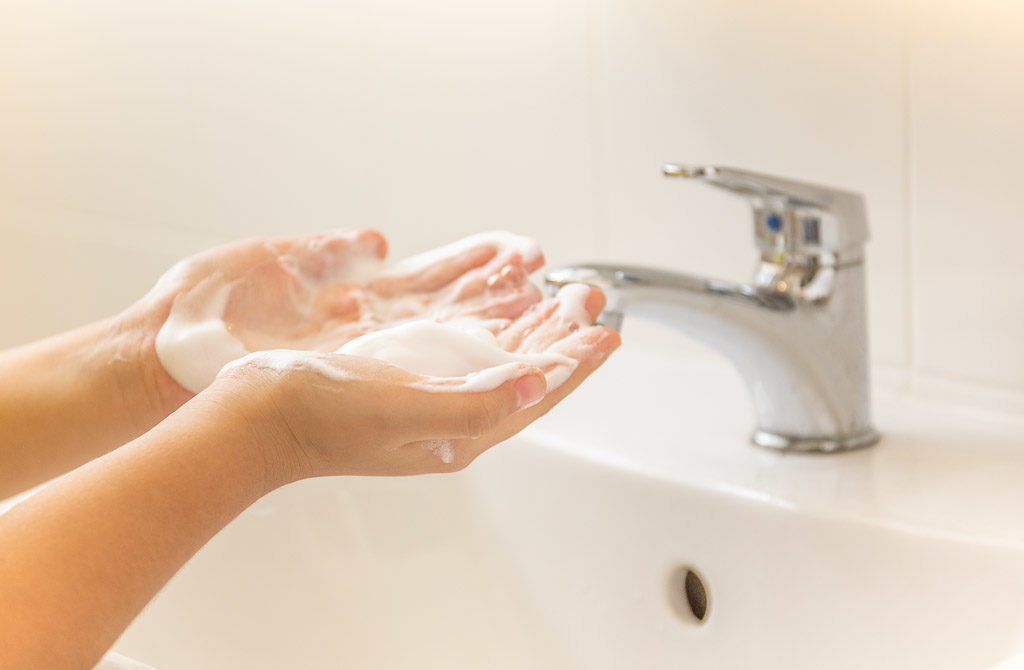 Child washing hand with soap and water